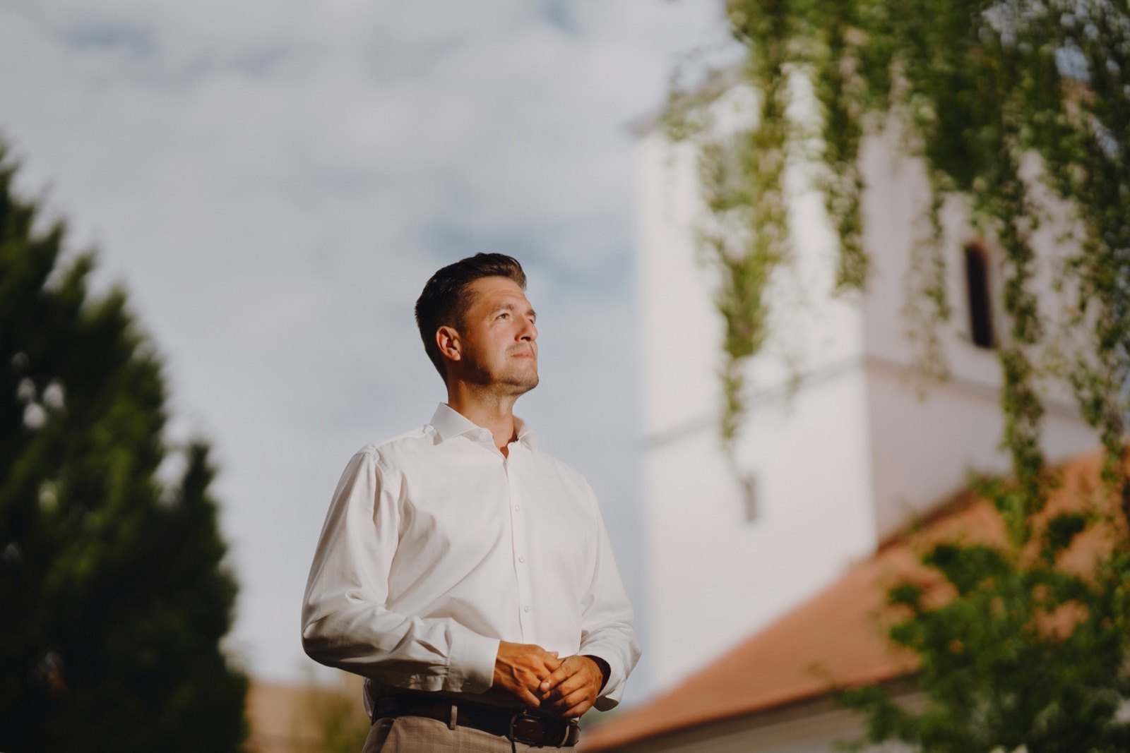 Roman Krištofík hľadí dopredu, v pozadí rozostrená veža senického kostola